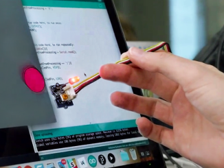 A hand holding a lighted stylus that is programmed by a computer